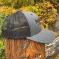 Deerwoode Reserve | A black trucker hat is sitting on top of a wooden post.