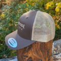Deerwoode Reserve | A brown and tan trucker hat on top of a stump.